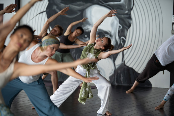 Dancers in a studio with a large circular mirror on the wall.