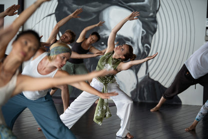 Dancers in a studio with a large circular mirror on the wall.