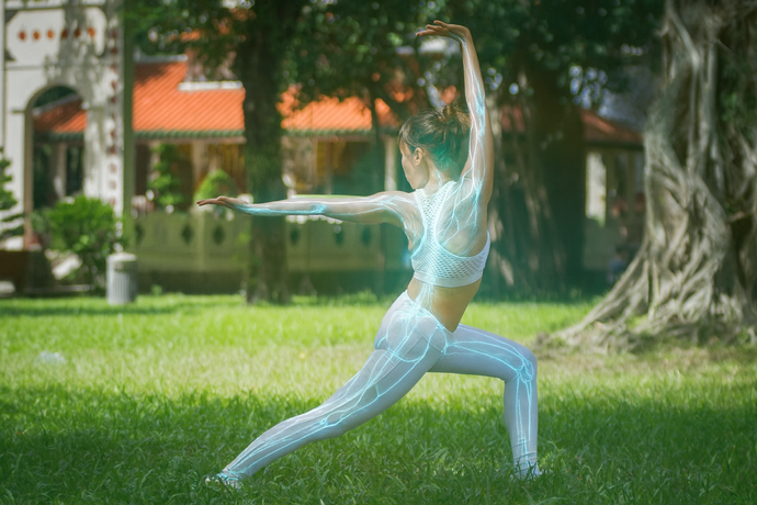 Person in a white outfit practicing yoga in a park with trees and buildings in the background
