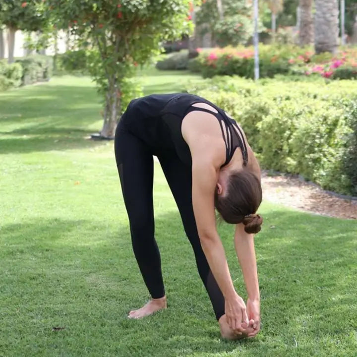 A student folds forward in Bowing to Heaven and Earth, hands at the front foot